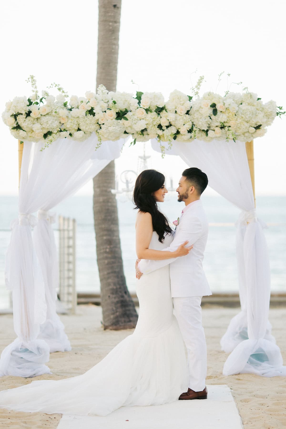 Key West beach wedding ceremony with floral arch and chairs